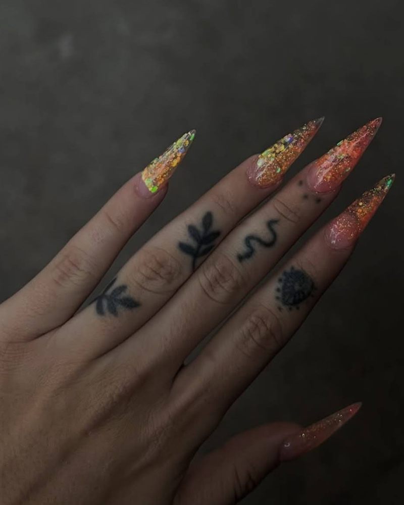 Uñas largas en punta con diseño full de glitter en tonos naranja y dorado
