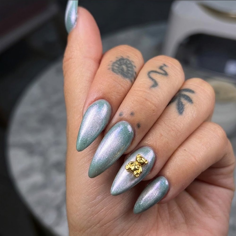 Uñas esculpidas almendra en verde menta cromado, con un osito dorado de adorno