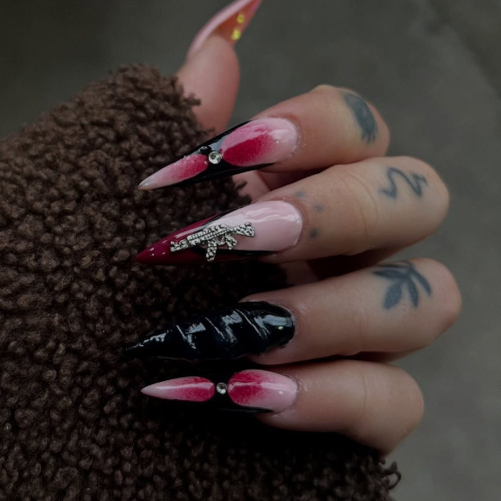 Uñas esculpidas stiletto largas en negro y rosa, con pedrería